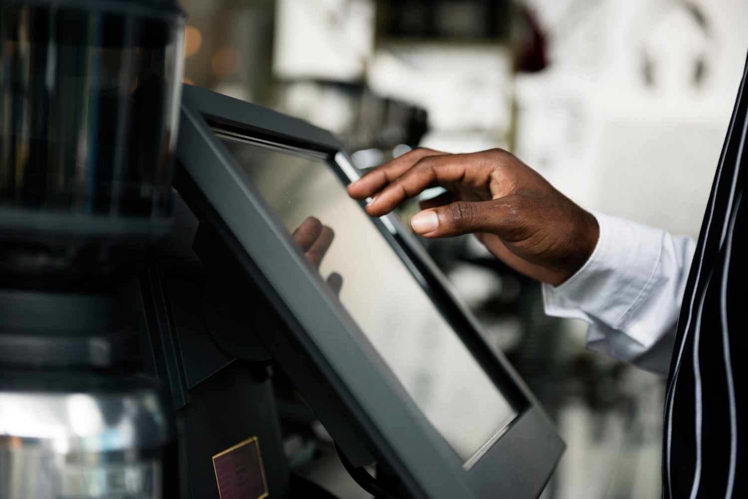 Cashier using a touch-screen POS machine in a Tanzanian shop